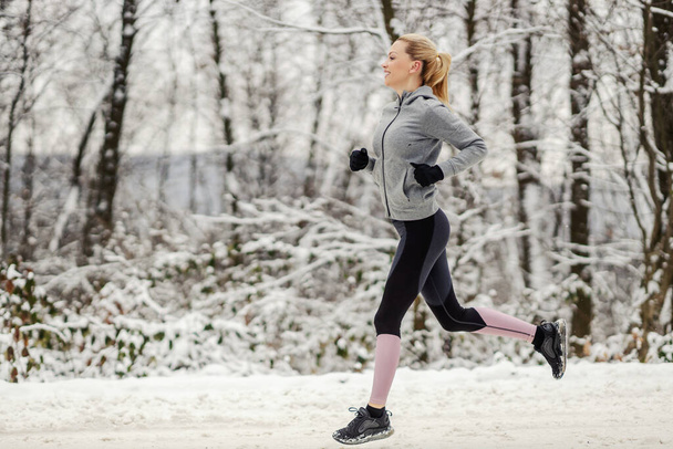 Karlı kış gününde doğada koşan sporcu kadın. Kış sporları, sağlıklı alışkanlıklar, kardiyo egzersizleri. - Fotoğraf, Görsel