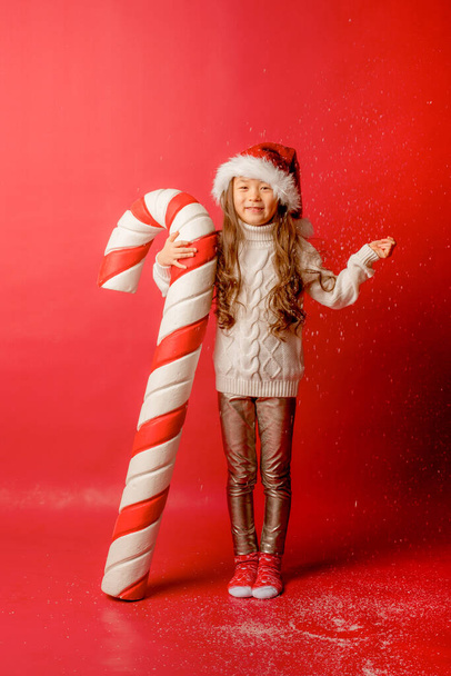 ragazza asiatico ragazza in Santa cappello su un rubinetto il fondo con un Grande caramello per catturare il neve - Foto, immagini