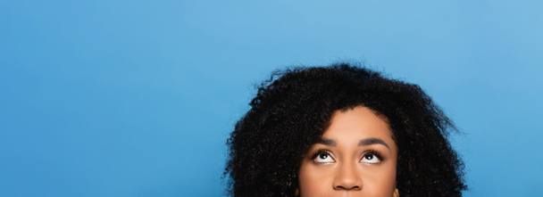 partial view of young african american woman looking up isolated on blue, banner - Fotografie, Obrázek