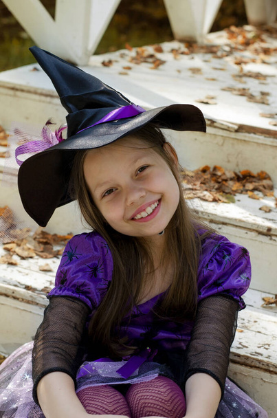Sorriso felice, ragazza seduta in costume da strega per strada - Foto, immagini