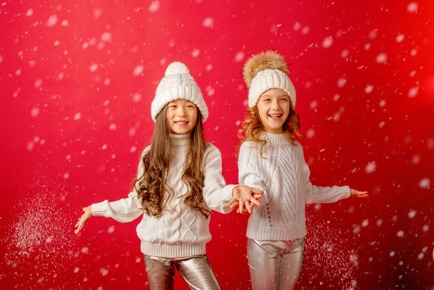 маленькие девочки, выдувающие снег на красном фоне - Фото, изображение