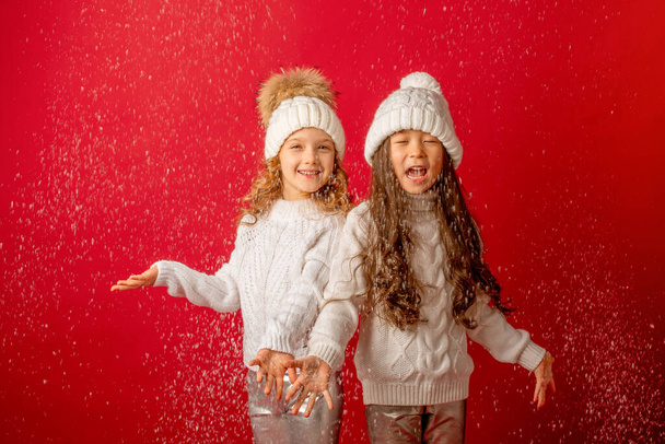 маленькие девочки ловят снег на красном фоне - Фото, изображение