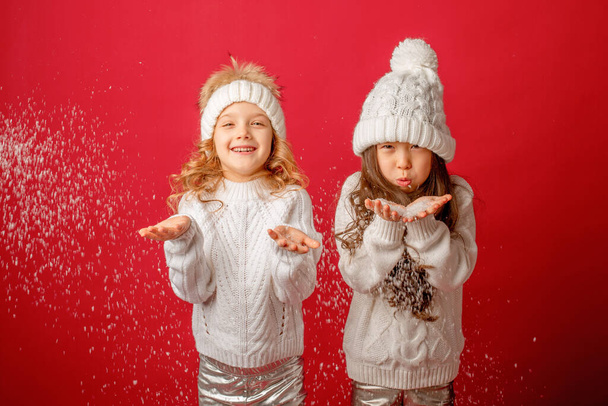 małe dziewczynki wieje śnieg na czerwonym tle - Zdjęcie, obraz