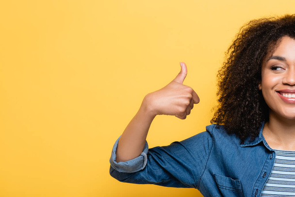 cropped view of cheerful african american woman showing thumb up isolated on yellow - Foto, Imagen
