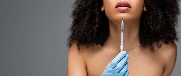 vue recadrée de la femme afro-américaine en gant de latex tenant la seringue avec injection de beauté isolé sur gris, bannière - Photo, image