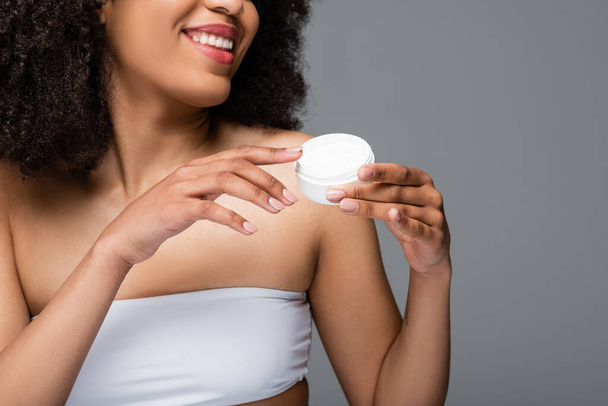 cropped view of african american woman in white top holding cosmetic cream isolated on grey - Photo, Image