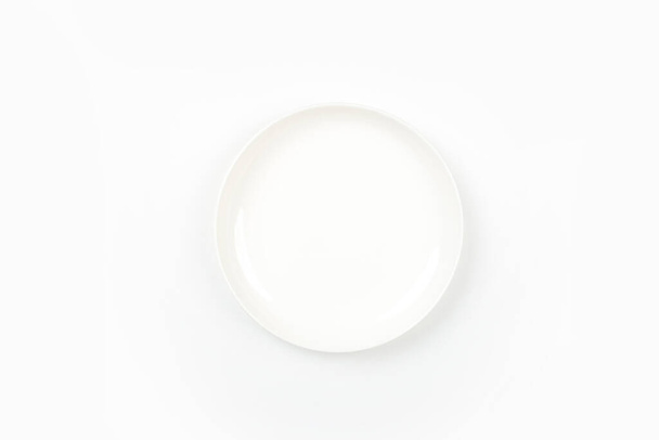 Λευκό πιάτο τοποθετείται σε λευκό φόντο, πάνω όψη - Φωτογραφία, εικόνα