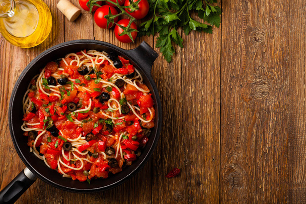 Italian spaghetti alla Pultanesca with tomatoes and olives. Served without meat and cheese. Top view. Natural wooden background.  - Foto, immagini