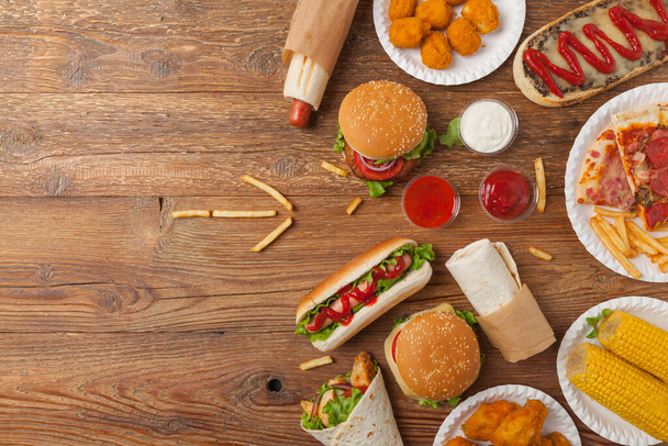 Mix of fast food, street dishes. Background with copy space. Top view. Natural wooden background.  - Foto, Bild