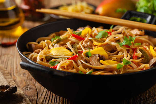 Fried chicken with mango and coconut milk with noodles. Prepared in a wok. Front view.  - Photo, image