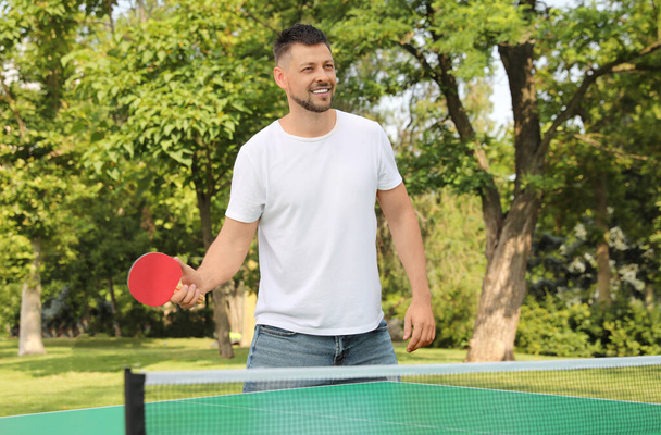 Happy man playing ping pong outdoors on summer day - Φωτογραφία, εικόνα