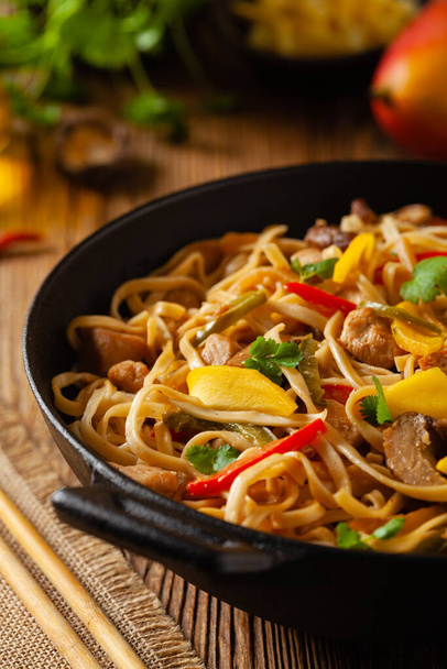 Fried chicken with mango and coconut milk with noodles. Prepared in a wok. Front view.  - Foto, imagen