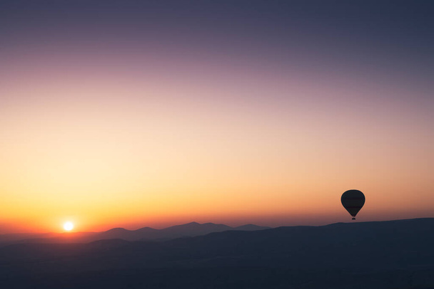 landscape with hot air balloons black silhouette rising up to the sky at sunrise with beautiful high mountain panorama in the background - Photo, Image