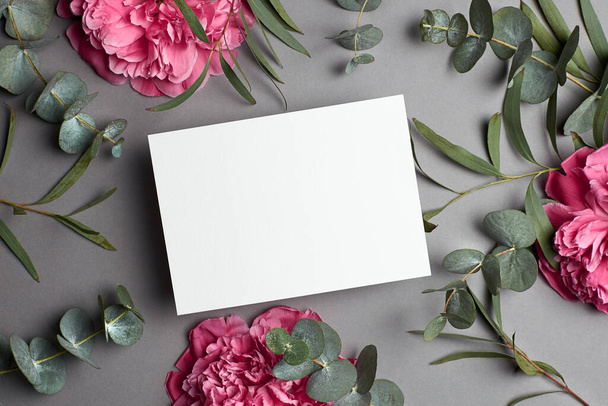 Wedding invitation or greeting card mockup with eucalyptus and pink peony flowers. - Фото, изображение