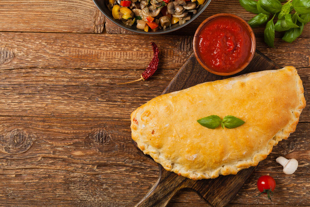 Italian calzone with mushrooms and ham. Top view.  - Фото, изображение