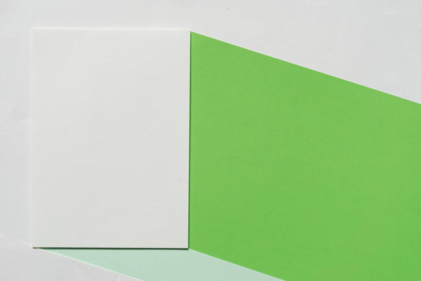 Вид сверху, плоский лай вертикальной бланковой белой макетной брошюры с зеленой и мятной бумагой на белом бумажном фоне. - Фото, изображение
