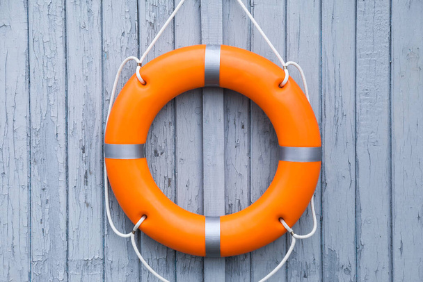Orange life buoy hanging on light wooden wall - Фото, зображення