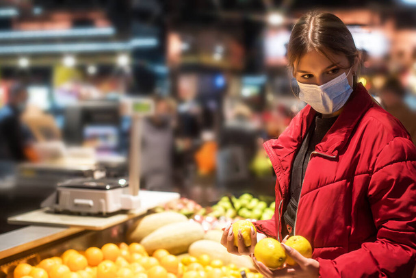 Girl wears protected mask in store. Shopping time during coronavirus outbreak. Girl in a medical mask. Quarantine and protection virus, flu, epidemic COVID-19. Coronavirus quarantine. - Photo, Image