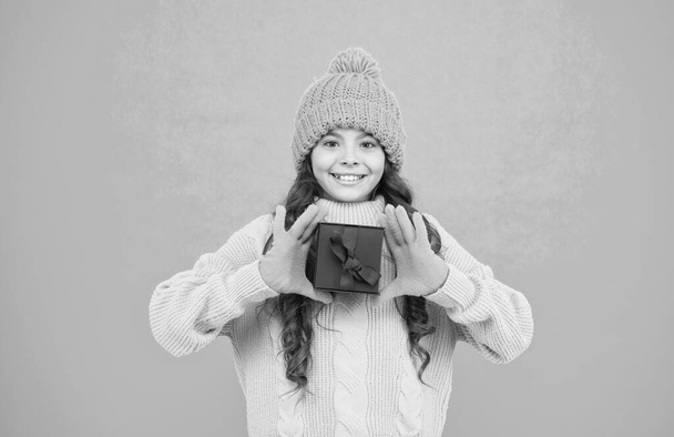 Feeling grateful for good gift. Winter holidays. Merry christmas. Child happy hold gift box. Kid girl wear warm hat delighted gift. Unexpected surprise. Celebrate birthday. Kid love birthday gift - Fotó, kép
