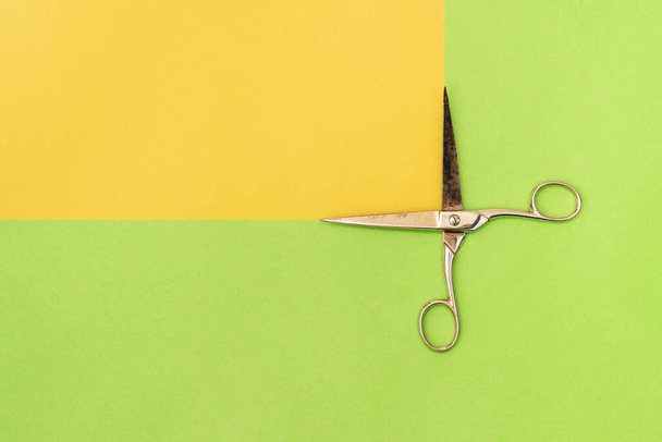 Colorful green and yellow paper background with metal scissors - Photo, Image