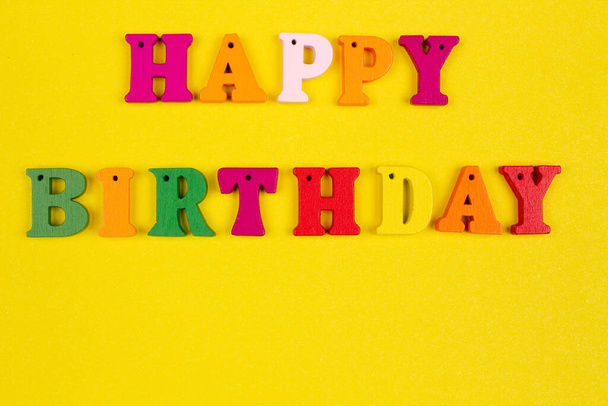 Modèle de slogan joyeux anniversaire avec espace de copie pour le texte avec nom sur fond jaune vif. Carte d'anniversaire de voeux avec des lettres colorées. Félicitations et vœux originaux pour les vacances. Gros plan - Photo, image