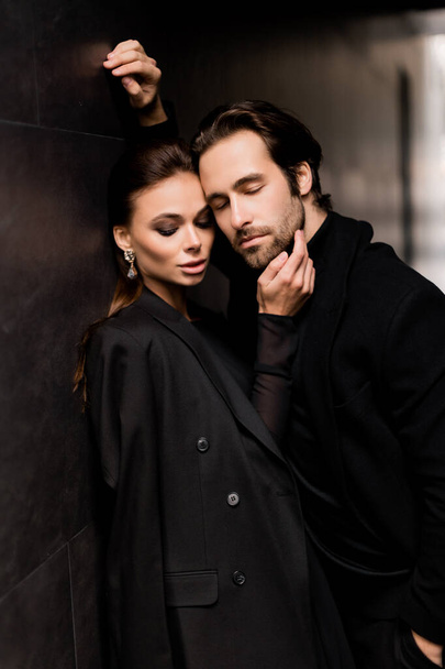young couple in a black suit and a jacket on a background of a dark wall - Fotografie, Obrázek
