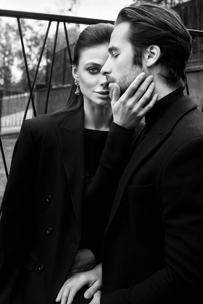 beautiful young couple in black suit and white shirt posing in studio - Zdjęcie, obraz