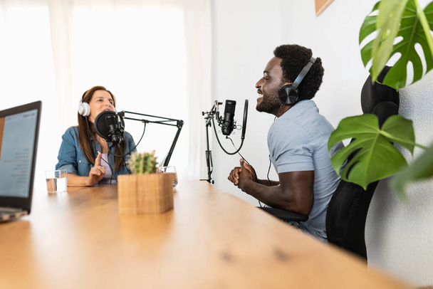 Multirassische Menschen, die einen Podcast mit Mikrofon und Laptop aus dem Heimstudio aufnehmen - Foto, Bild