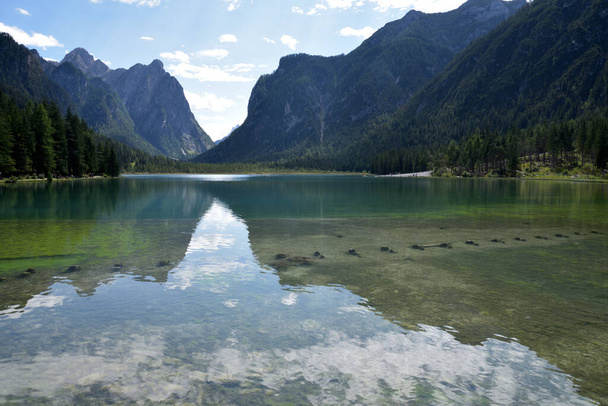 Sky and mountains reflected in the waters of Lake Dobbiaco on a summer day - Photo, Image
