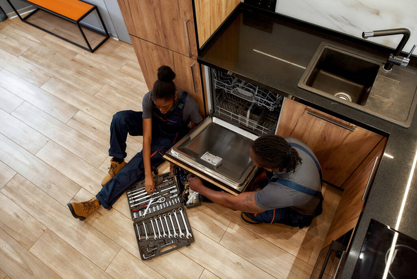 Above view multiracial repair persons fixing dishwasher - 写真・画像