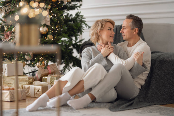 adult man and woman sit on the floor near the couch and hug - Foto, immagini