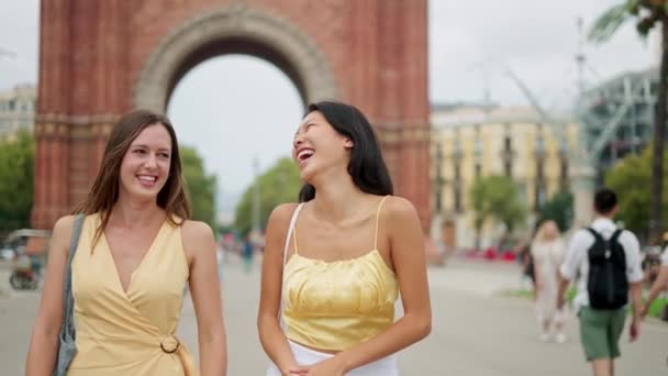 Kaksi sekarotuinen nuori onnellinen nainen nauraa vitsi matkustaessaan ja sightseeing kaupungissa - Materiaali, video