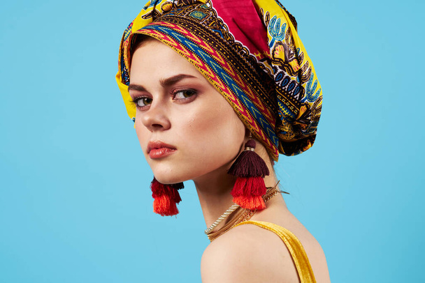 beautiful woman  with ethnicity multicolored headscarf on  blue background. High quality photo - Photo, Image