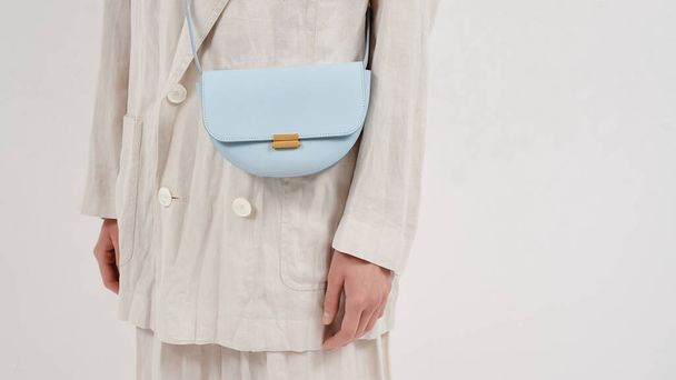 Bolso de mano Chica de lino beige con bolso de cuero azul sobre fondo blanco. Bolso de hombro. Copiar espacio. Foto de formato web ancho. - Foto, imagen