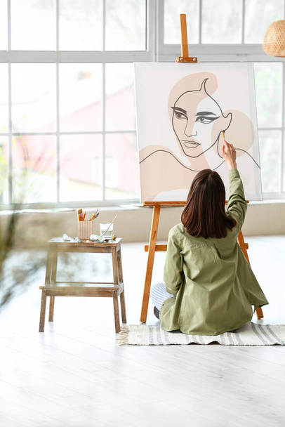 Young female artist painting in workshop - Fotó, kép