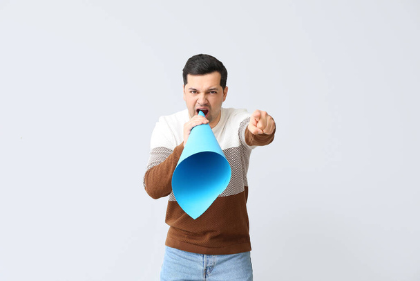 Protesting young man with paper megaphone on light background - Photo, Image
