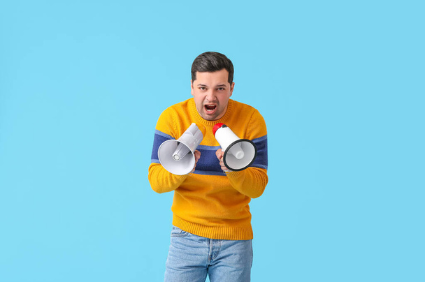 Protesting young man with megaphones on color background - Φωτογραφία, εικόνα