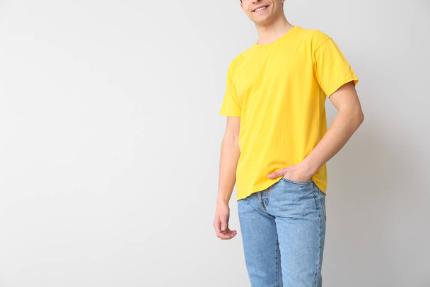 Knappe jongeman in stijlvol t-shirt op lichte achtergrond - Foto, afbeelding