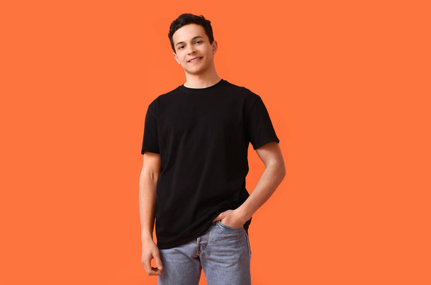 Knappe jongeman in stijlvol t-shirt op kleur achtergrond - Foto, afbeelding