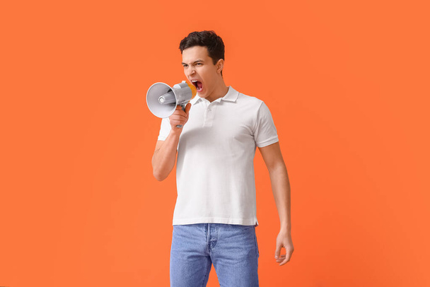 Protesting young man with megaphone on color background - Foto, Bild