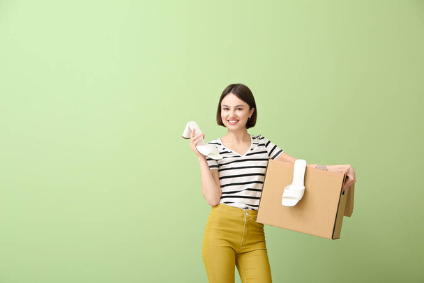Young woman with wardrobe box and shoes on color background - Foto, Imagem
