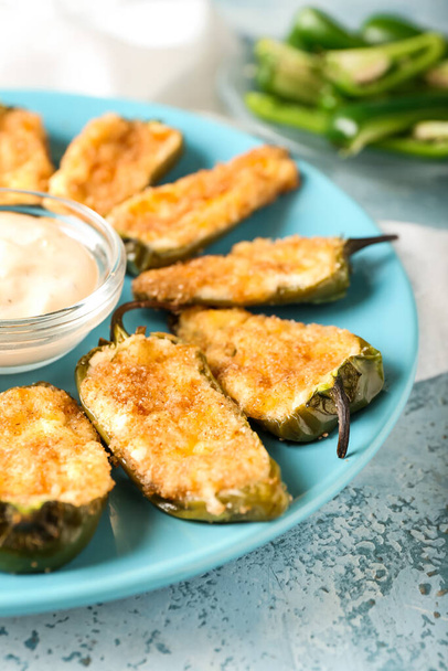Delicious jalapeno poppers and sauce in plate on color background, closeup - Photo, Image