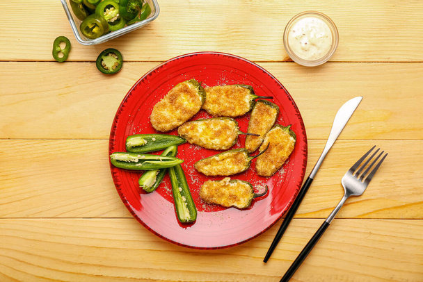 Plate with tasty jalapeno poppers and sauce on wooden background - Photo, Image