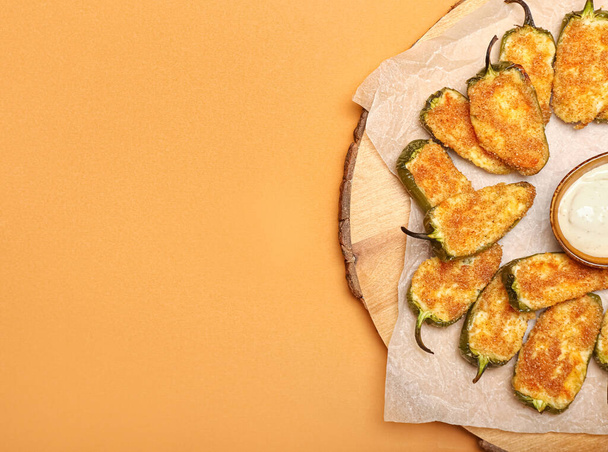 Board with tasty jalapeno poppers and sauce on color background - Photo, Image