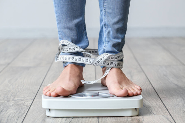 Jonge vrouw met anorexia meten van haar gewicht thuis - Foto, afbeelding