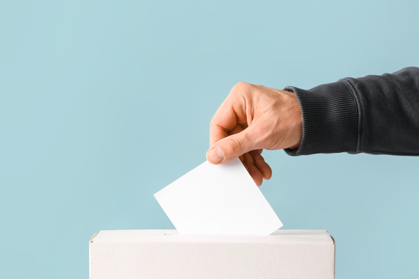 Voting man near ballot box on color background - Photo, Image