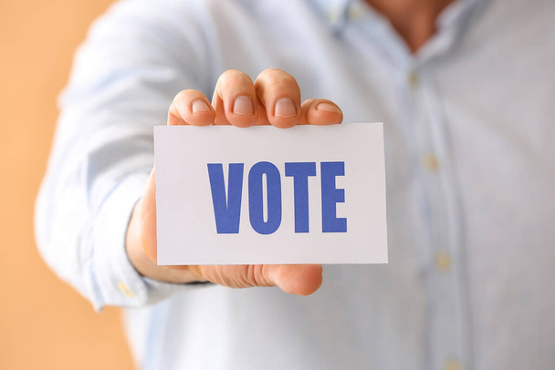 Человек держит бумагу с текстом VOTE, крупным планом - Фото, изображение