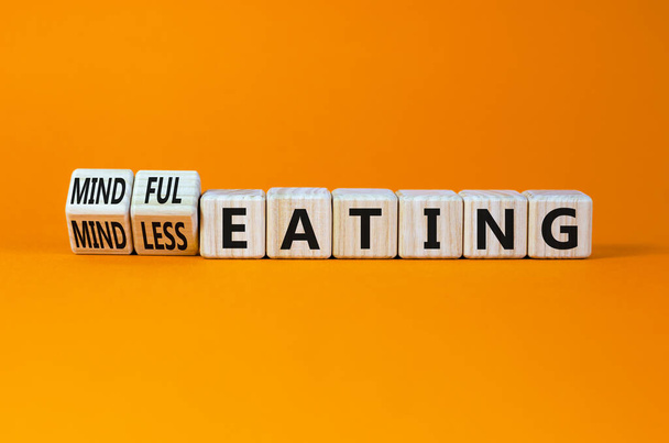 Mindful or mindless eating symbol. Turned wooden cubes and changed words mindless eating to mindful eating. Beautiful orange background, copy space. Medical and mindful or mindless eating concept. - Photo, Image