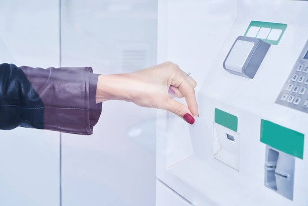Female hand uses contactless payment by credit card to withdraw money from ATM - Foto, Imagen