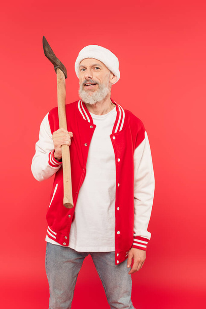 hombre de mediana edad en sombrero de santa con hacha en rojo - Foto, imagen